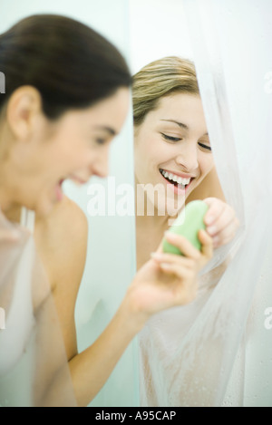 Zwei junge Frauen in Duschen, eine Übergabe Stück Seife zum zweiten Stockfoto