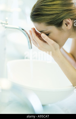 Frau waschen Gesicht über Waschbecken Stockfoto