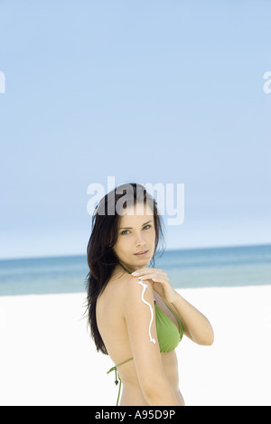 Frau, die Anwendung von Sonnenschutzmitteln, am Strand, Seitenansicht zu bewaffnen Stockfoto