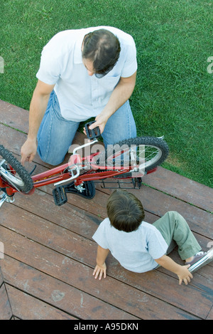 Vater Sohn Fix Fahrrad helfen Stockfoto