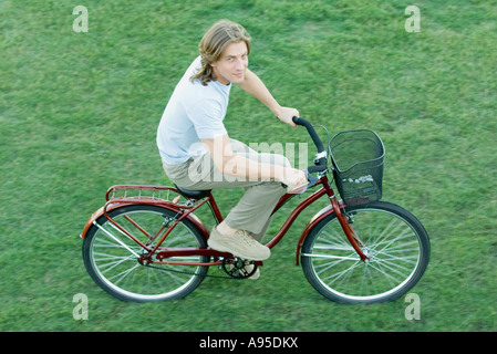 Junger Mann Reiten Fahrrad auf Rasen, erhöhte Ansicht Stockfoto