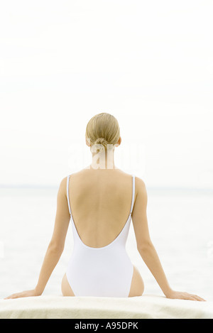 Frau im Badeanzug sitzt auf Sessel, Rückansicht Stockfoto