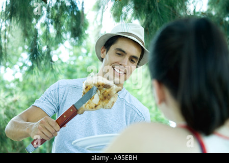 Man servieren Mädchen Stück gegrilltes Hähnchen Stockfoto