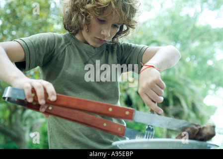 Junge Stück Fleisch vom Teller aufnehmen Stockfoto