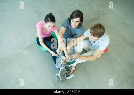 Teenager Freunde mit Beinen trat an Knöcheln, Schnürsenkel von Canvas-Schuhe binden Stockfoto