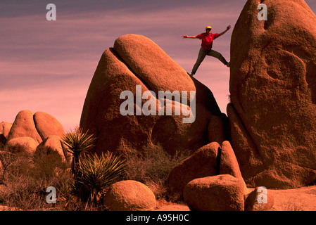 Frau Klettern / balancieren auf einem Felsen, Joshua Tree Nationalpark, Kalifornien, USA Stockfoto