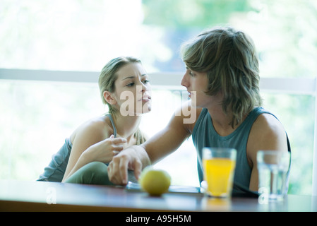 Junges Paar Ausübung Kleidung, sitzen nebeneinander, mit gesunden Snack und Blick auf Magazin Stockfoto