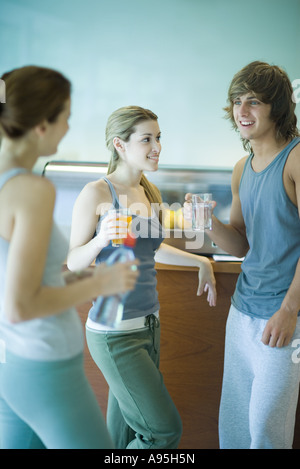 Junge Erwachsene tragen Ausübung Kleidung, in der Cafeteria stehen, mit gesunden Snack und im Chat Stockfoto