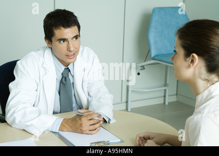 Arzt gegenüber Patientin sitzt Stockfoto