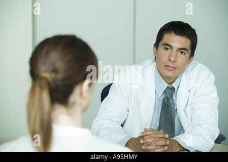 Arzt gegenüber Patientin sitzt Stockfoto