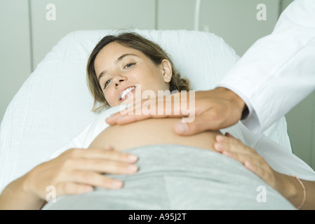 Schwangere Frau auf Rücken, des Arztes Hand auf Bauch liegend Stockfoto