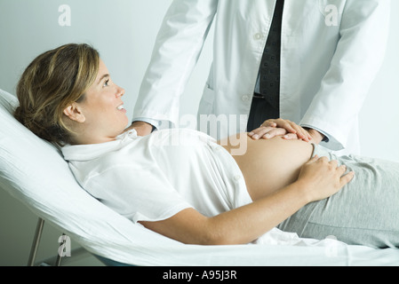 Schwangere Frau auf Rücken, des Arztes Hand auf Bauch liegend Stockfoto