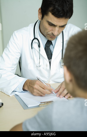 Arzt gegenüber jungen, schreiben in Zwischenablage Stockfoto