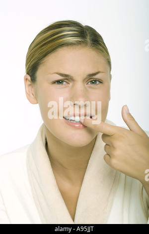 Junge Frau trägt Bademantel, Zähne berühren und gerunzelter Stirn Stockfoto