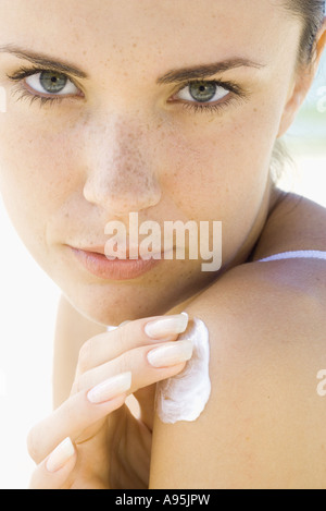 Junge Frau, die Anwendung von Sonnenschutzmitteln, Schulter Stockfoto