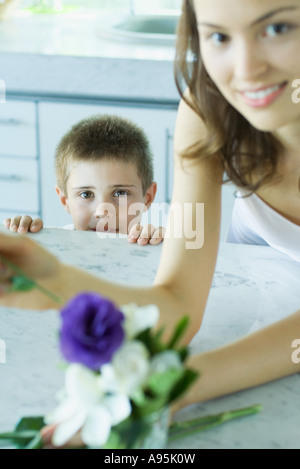 Junge Frau macht frischen Blumenschmuck, neben jungen, Lächeln Stockfoto