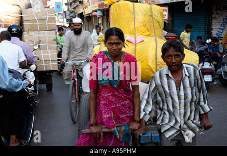 Indische Frau zieht beladen Wagen durch die Straßen von Ahmedabad, Gujarat, Indien Stockfoto