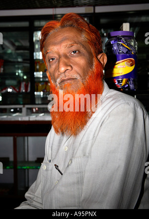Muslimischer indischer Ladenbesitzer mit orangefarbenem Bart und Haaren, Ahmedabad, Gujarat, Indien Stockfoto