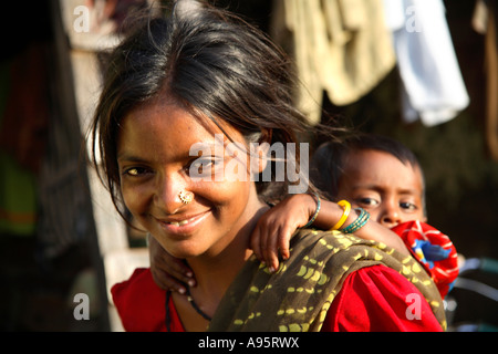 Indische Frau, die Kind auf dem Rücken außerhalb der Shanty Home, D'Mello Road, Mumbai, Indien Stockfoto