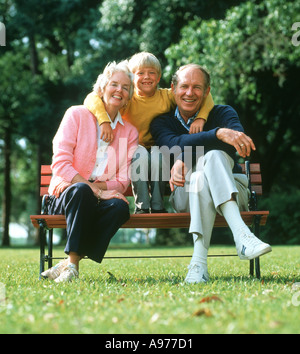 Älteres Paar mit Enkel auf Holzbank im park Stockfoto