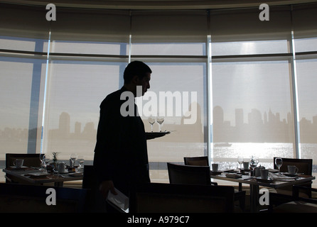 Ein Kellner in der Silhouette geht eine Bank von Windows in einem Hotel auf dem Hudson river Stockfoto