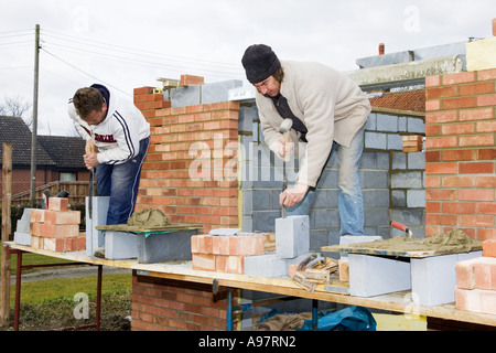 Maurer mit Stemmeisen Kropf und eine Säge um ^ schneiden Bausteine Stockfoto