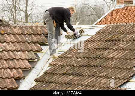 ein Bauherr passende Fliesen auf einem Dach einer Heim-Erweiterung Stockfoto