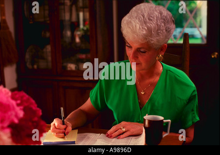 Ältere Frau, die arbeitet am Esstisch zu Hause Stockfoto