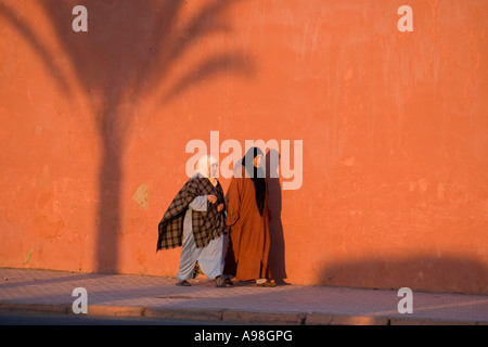 Zwei Frauen gehen neben der Festungsmauer, Marrakesch, Marokko Stockfoto