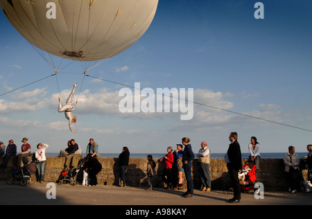 Eine riesige Helium-Ballon mit einer Antenne Trapezkünstler unter driftete über Zuschauer auf Dorset s Jurassic Coast Arts ausgesetzt Stockfoto