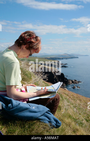 junge Frau studieren eine Landkarte vor einem schönen Klippe Landschaft auf der Dingle-Halbinsel im Westen Irlands Stockfoto