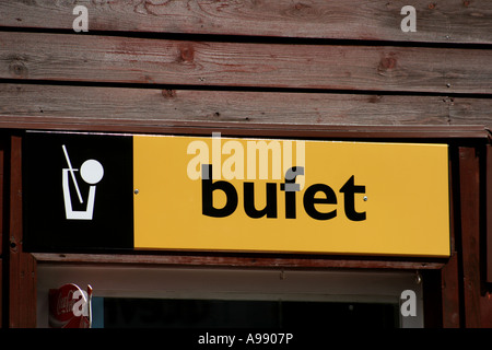 Ein gelbes und schwarzes „Bufet“-Schild an einer Holzwand, das auf ein Restaurant mit Speisen oder Getränken hinweist. Stockfoto