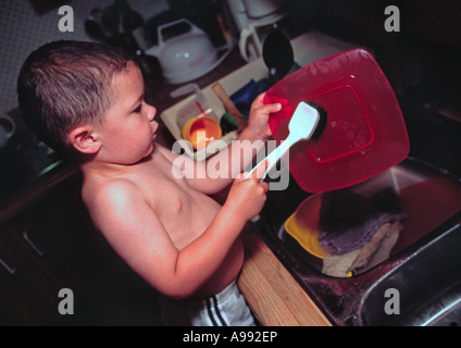 3 Jahre alter Junge Geschirrspülen Stockfoto