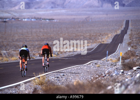 Mann und Frau Radfahren sind die einzigen Menschen auf eine lange einsame zweispurige Straße durch Death Valley CA Stockfoto