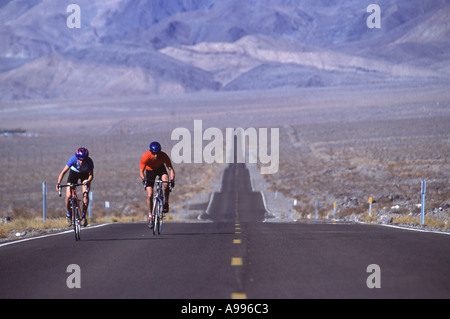 Mann und Frau Radfahren sind die einzigen Menschen auf eine lange einsame zweispurige Straße durch Death Valley CA Stockfoto