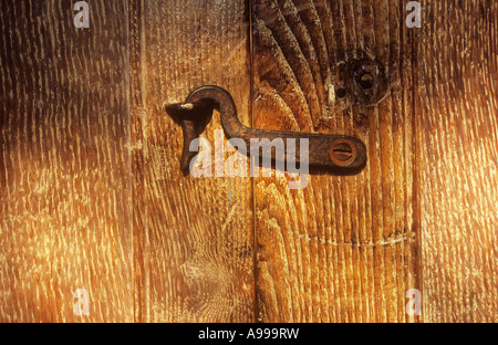 Nahaufnahme von kleinen alten getrübt Metallhaken oder Verschluss hakte in angrenzenden Schleife getragen gemaserte Holz Tür geschlossen zu halten Stockfoto