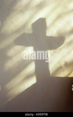 Schatten des Kreuzes werfen auf Creme lackiert rauhe Wand mit Projektion von einfachen Diamant verbleit Glasscheiben Kirchenfenster Stockfoto