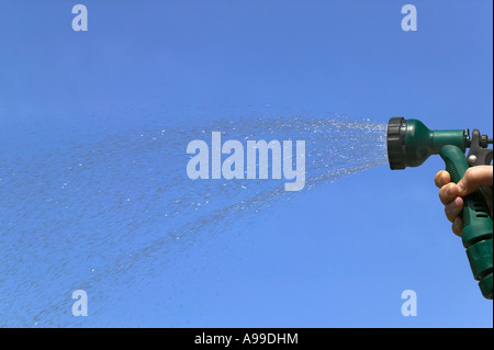 Wasser aus einem Gartenschlauch Sprinkler gegen ein strahlend blauer Himmel sprühen Stockfoto