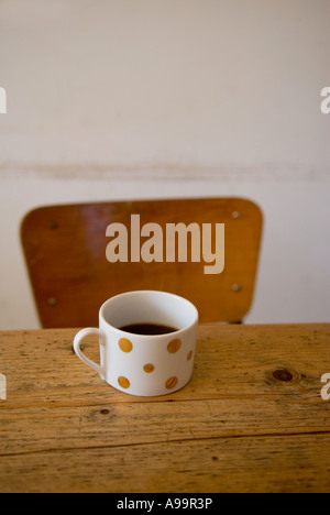 Eine einzige Tasse Kaffee auf einem Küchentisch Kiefer mit einem Stuhl im Hintergrund Stockfoto
