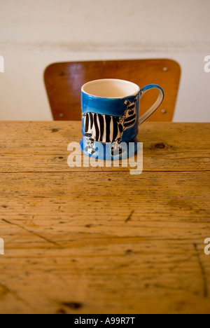 Eine einzelne Tasse auf einem Küchentisch Kiefer mit einem Stuhl im Hintergrund Stockfoto