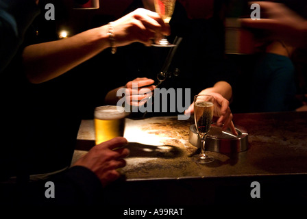 Eine intime Nahaufnahme von Händen und ein paar Gläser Sekt und Bier auf eine düster beleuchteten bar Stockfoto