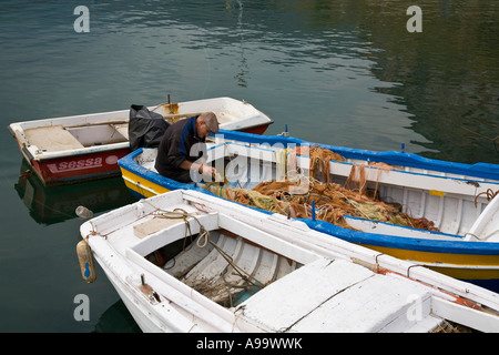 Sizilianische Fischer sitzt im Fischerboot ausbessern Fischernetze in der Marina auf der Mar Tirreno Cefalu-Sizilien-Italien Stockfoto
