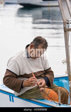 Sizilianische Fischer sitzen im Boot ausbessern Fischernetze in der Marina auf der Mar Tirreno Cefalu-Sizilien-Italien Stockfoto