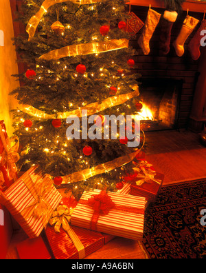 VERPACKTE WEIHNACHTSGESCHENKE UNTER DEKORIERTEN CHISTMAS BAUM KAMIN IM HAUS Stockfoto