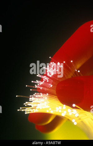 BELEUCHTETEN SPITZEN DER OPTISCHE FASERSTRÄNGE (© KECK MAURER & SCHULTZ / CORNING GLASS WORKS 1970) ZWISCHEN WOMANS FINGER STATT Stockfoto