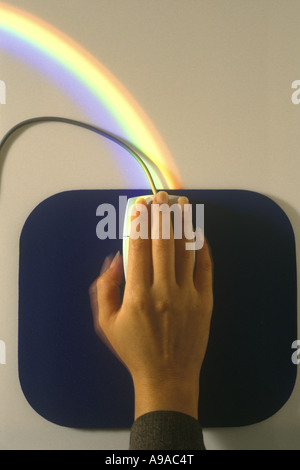 WOMANS HAND AUF PERSONAL COMPUTER-MAUS MIT REGENBOGEN Stockfoto