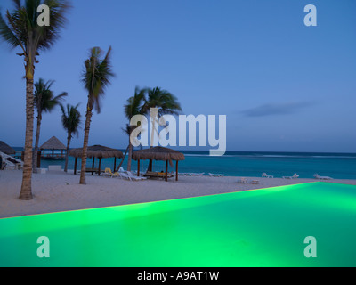 Mexiko Quintana Roo Yucatan Halbinsel Akumal Riviera Maya-Infinity-Pool beleuchtet durch den Rand von einem Strand mit dem Meer in der Stockfoto