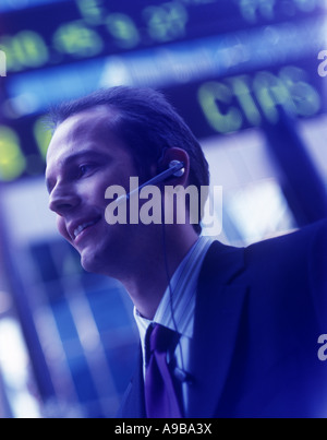 GLÜCKLICH LÄCHELND BÜROANGESTELLTER BÖRSE TICKER DISPLAY STANDBY NACHSCHLAGEN Stockfoto