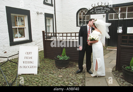 Brautpaar unter dem küssen Tor nach ihrer Hochzeit in alten Schmiede in Gretna Green Schottland Stockfoto