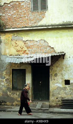 Ältere Frau, die vorbei an alten verfallenden Gebäude, hängen kann Ngang St, Altstadt in Hanoi, Vietnam Stockfoto